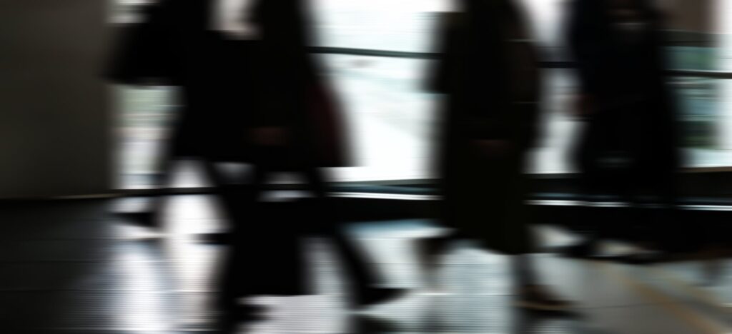 Abstract blurred motion of people walking indoors, depicting urban life and busy routines.
